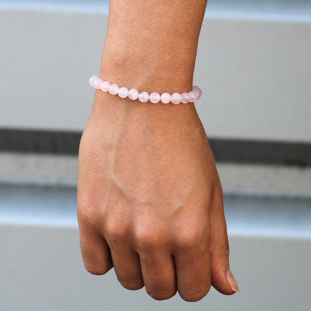 Bransoletka z koralików z różowego kwarcu pokazana na ręce kobiety.