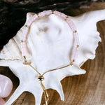 Bransoletka z różowym kwarcem pokazana od góry na białej muszli. 